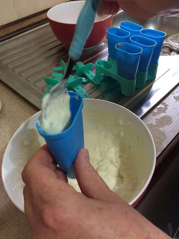 Adding the banana and yoghurt mixture to the ice blocks moulds.