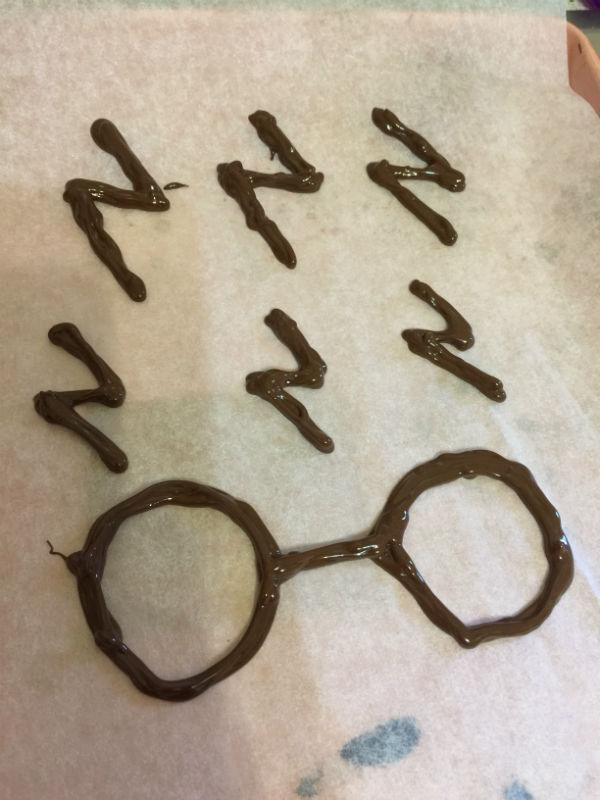 The dark chocolate that I piped to form the decorations on the Harry Potter Cake. I got the exact shapes from a printed download and copied that. Once done I put in the fridge to set.