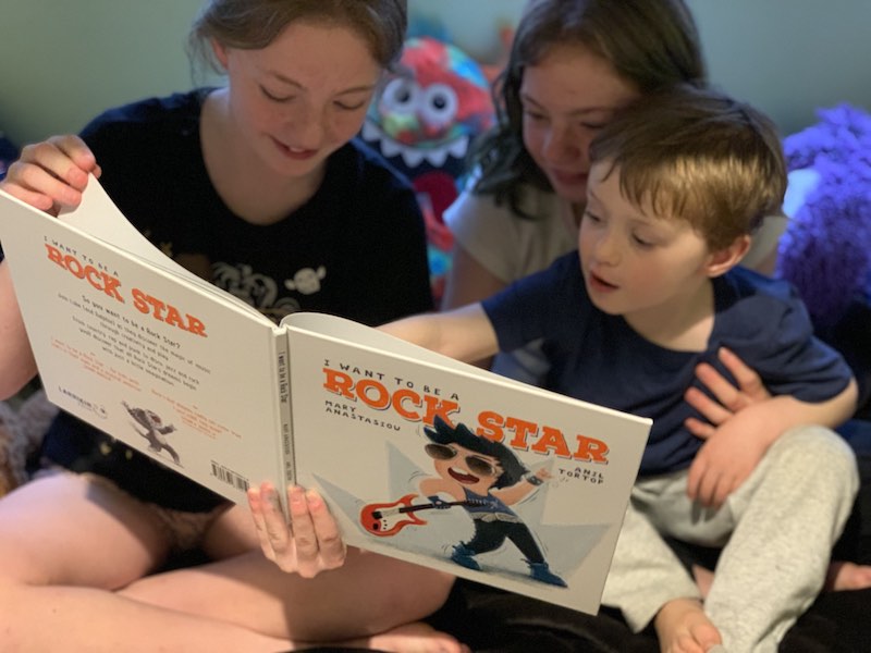 Big sisters reading their little brother I Want to be a Rock Star